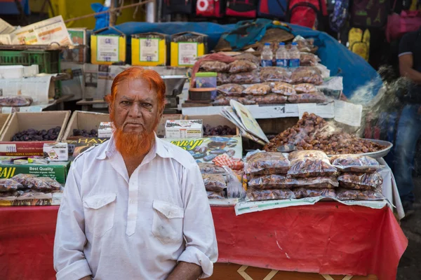 Indian vendor  sits next to street stall