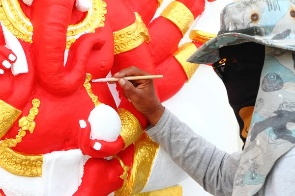 Muralist repair a painting on the wall of hindu god