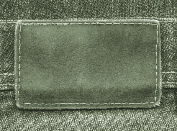 Green  leather label on  jeans background