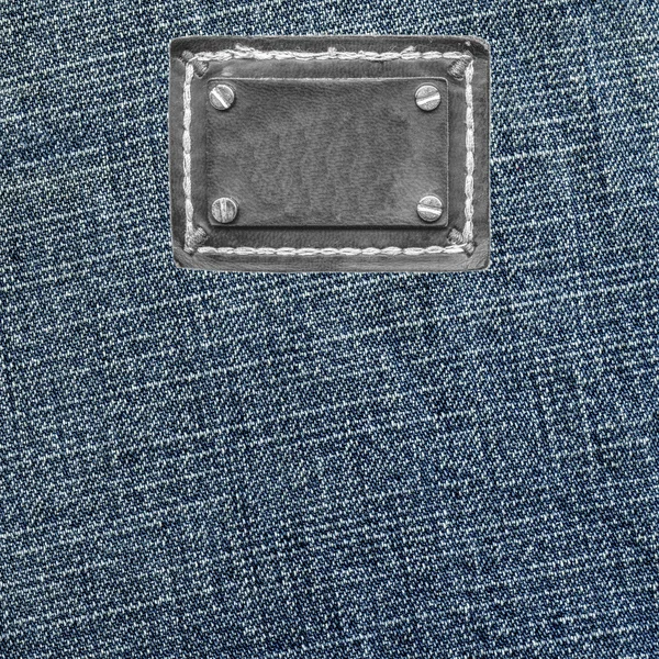 Blue denim texture, blank black leather label