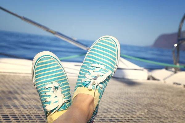 Woman relaxing on a catamaran sailboat trampoline with her feet crossed
