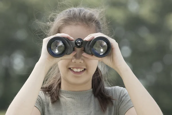 Pretty young girl exploring the environment with a binocular