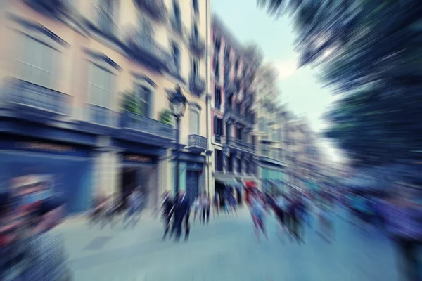 Abstract background. Pedestrians walking - rush hour in Barcelona, Spain.  Radial zoom blur effect defocusing filter applied, with vintage instagram look.