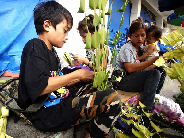 Vendors prepare palm leaves to be sold to church patrons