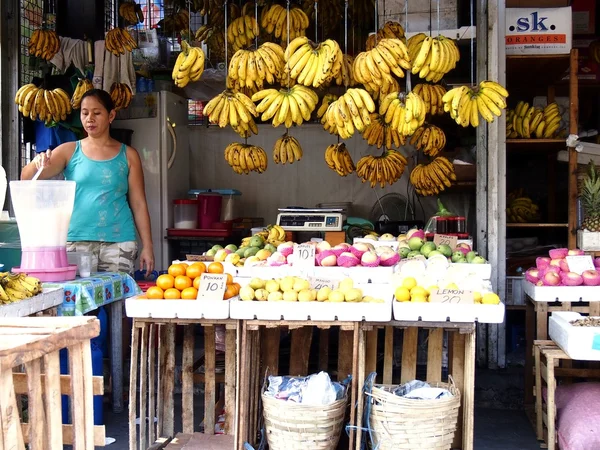 A vendor prepares fruit juice in her fruit stand in a market