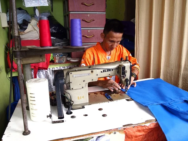 A tailor works on a dress with his sewing machine