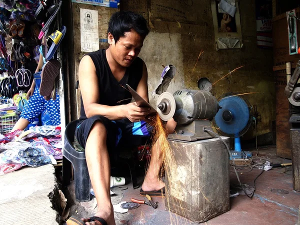 A tinsmith sharpens a saw in his shop