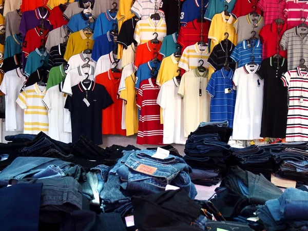 Colorful polo shirts and piles of denim jeans on display at a clothes store