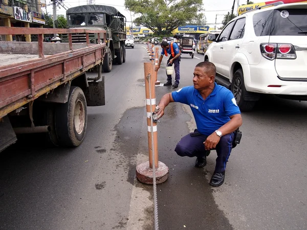 City government workers clean road safety poles