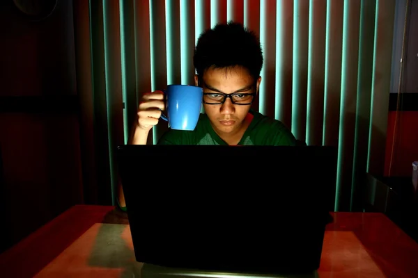 Young Teen holding a coffee mug in front of a laptop computer