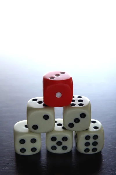 One Red game dice on top of stacked five white game dice