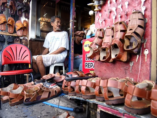 Old man sells a variety of  handcrafted footwear