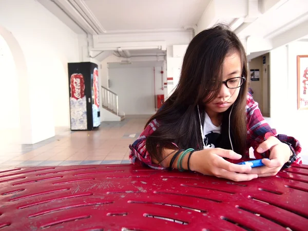 A young girl uses her cellphone or smartphone at a study hall in an HDB building in Tampines, Singapore