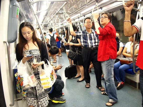 Commuters or passengers inside the MRT pass the time on their smartphone or cellphone.