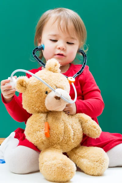 Girl caring for her teddy bear with a stethoscope