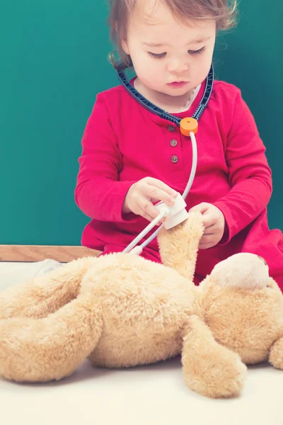 Girl caring for her teddy bear with a stethoscope