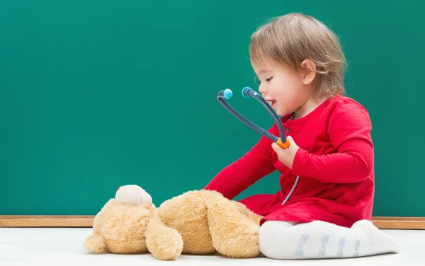 Girl caring for her teddy bear with a stethoscope
