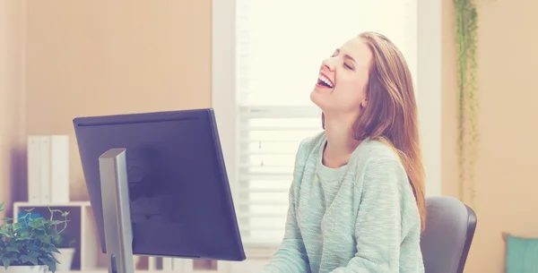 Young woman laughing in her home office