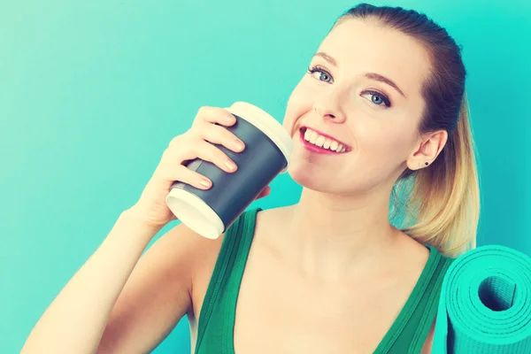 Woman holding coffee cup and yoga mat