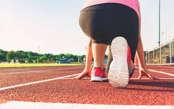 Female athlete on the starting line of a stadium track