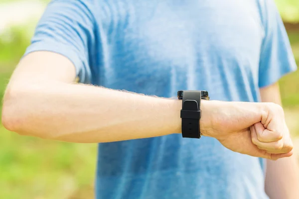 Male jogger outside looking at smart watch