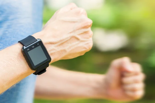 Male runner jogging outside with his smart watch