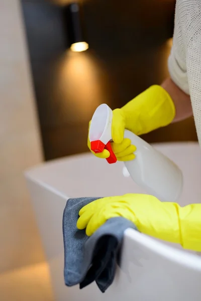 Hands with yellow rubber protective gloves cleaning bath