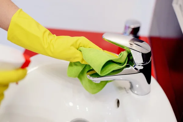 Female hands with rubber protective gloves cleaning tap