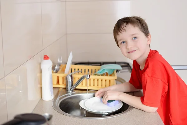 Smiling 7 year old boy washes dishes