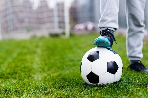 Feet of child on football / soccer ball on grass