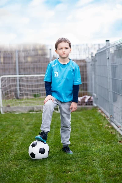 7 years boy - footballer with his feet on football ball