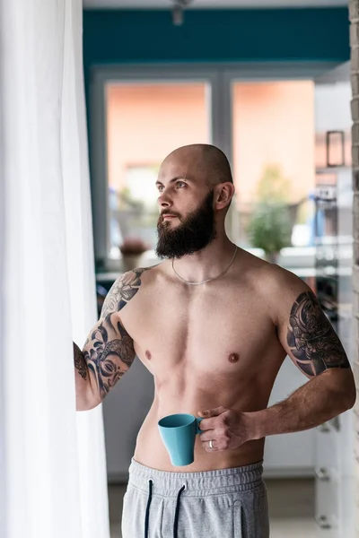 Muscular bearded man drinking coffee