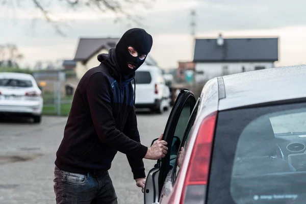 Car thief entering the vehicle and stealing a car.