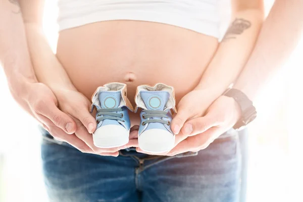 Mom and dad holding little baby shoes
