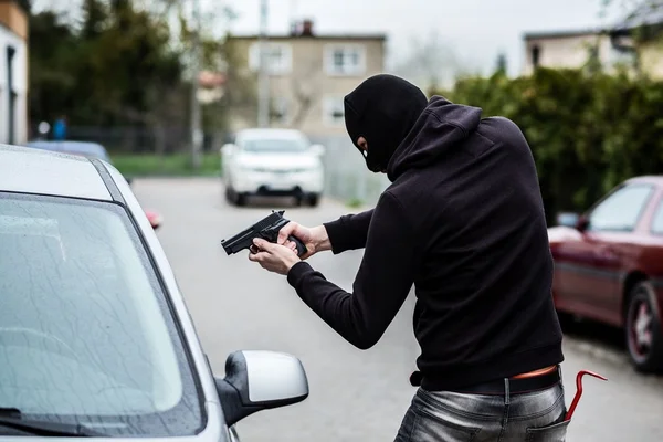 Car thief pointing a gun at the driver