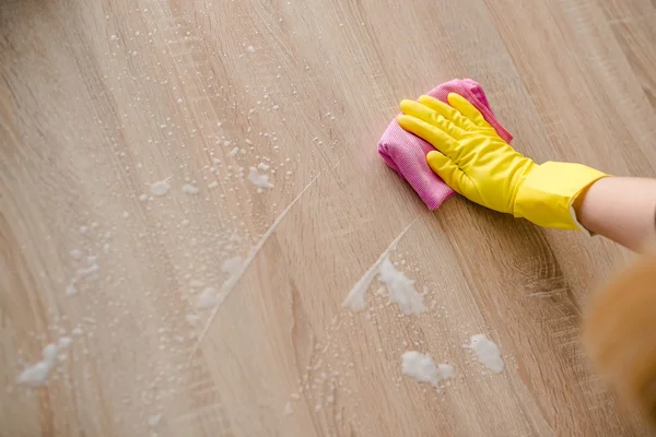 Woman in yellow rubber gloves cleaning table