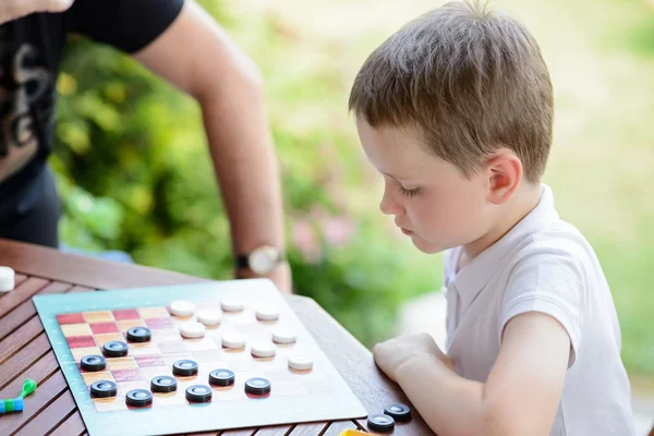 Little boy playing checkers board game