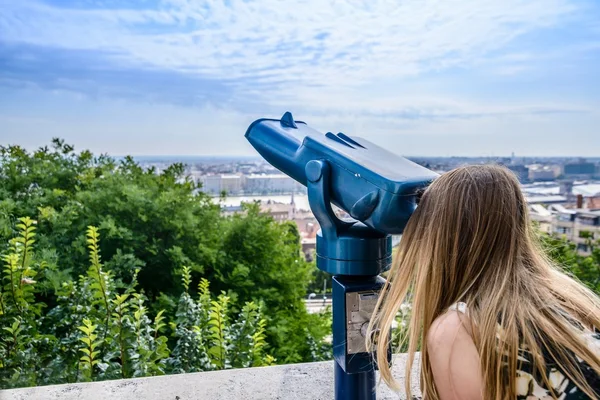 Woman looking through pay telescope for tourists