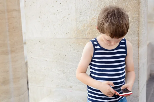 Little 7 years old boy playing mobile games on smartphone