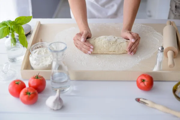 Woman kneading pizza dough on wooden pastry board