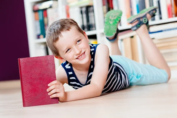 Seven years old boy reading a book in library.