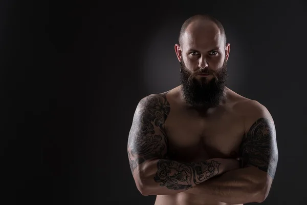 Upset muscular man with numerous tattoos