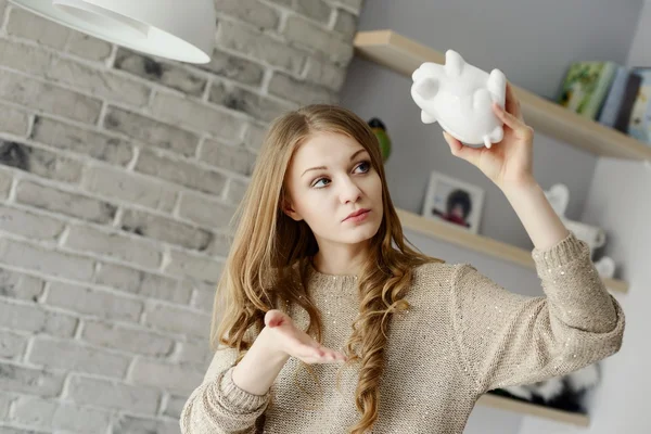 Woman trying to find more money in the piggy bank