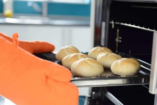 Hands putting in the oven bread rolls