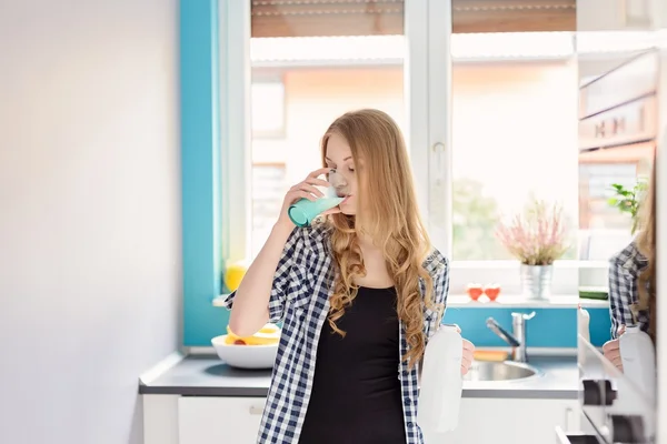 Young blond woman drinking milk from the glass.