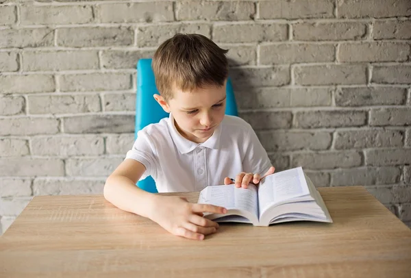 6 year old boy in a white polo shirt reading a book