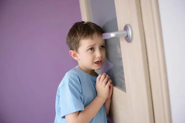 Crying, frightened child listening to a parent talking through the door