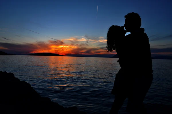 Silhouette of a couple kissing over sea sunset background