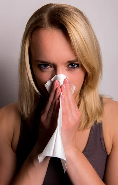 Young woman blows her nose