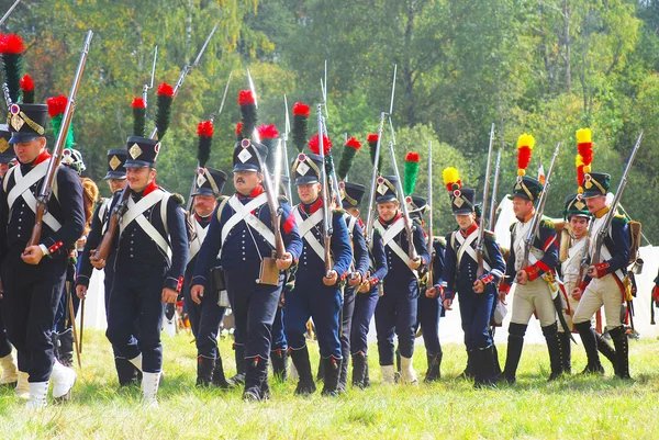 Reenactors dressed as Napoleonic war soldiers stand on the battle field.